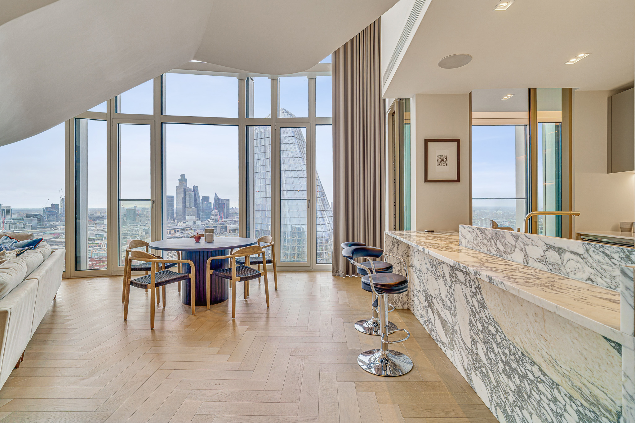 Open-Plan Kitchen & Living Room | Property Photography London Luxury open-plan kitchen and living area with marble island, floor-to-ceiling windows and panoramic London skyline views, professionally photographed for a premium residential property.